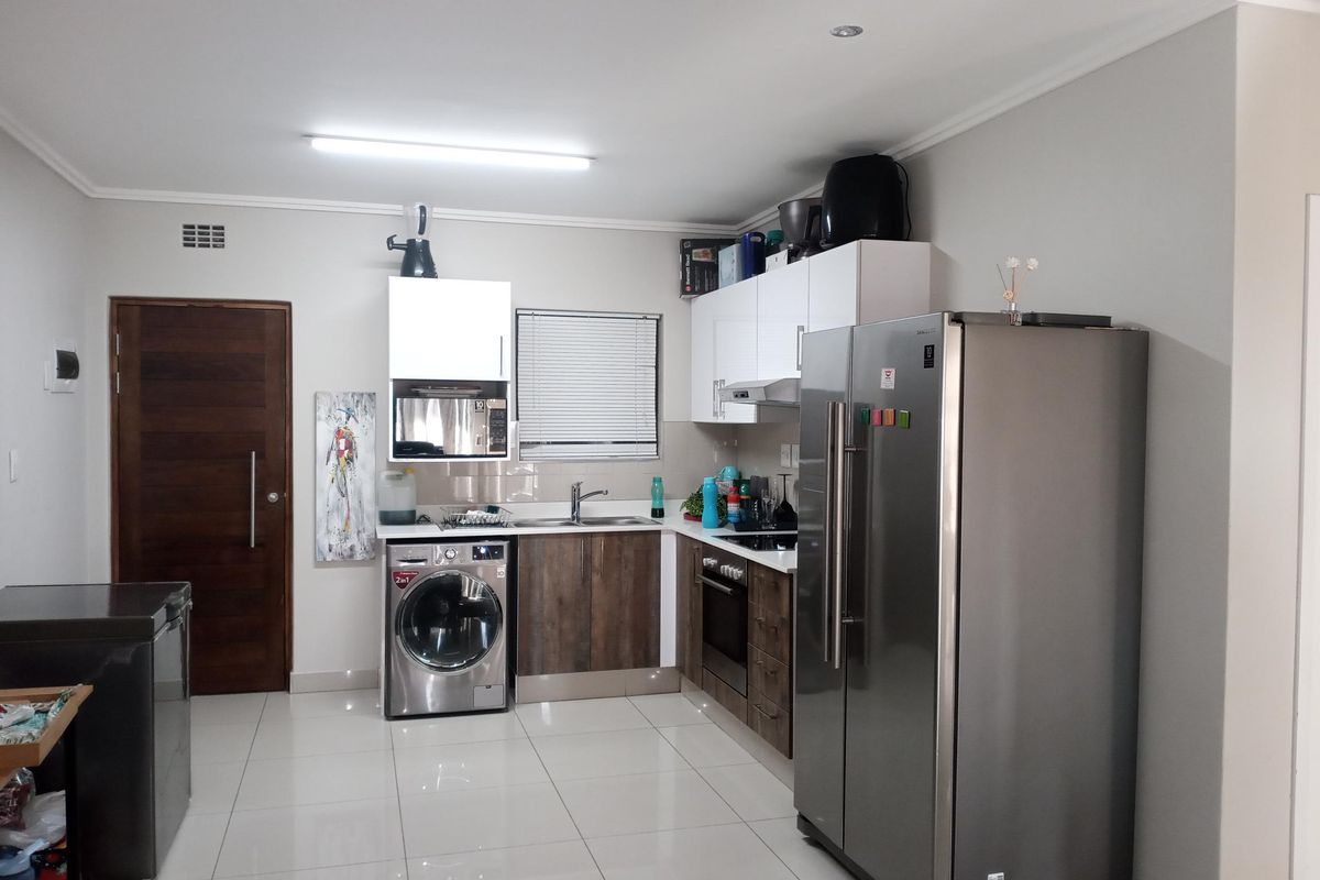 A functional kitchen featuring modern cabinetry, built-in oven and hob, stainless steel sink, and tiled flooring, providing a clean and practical workspace.