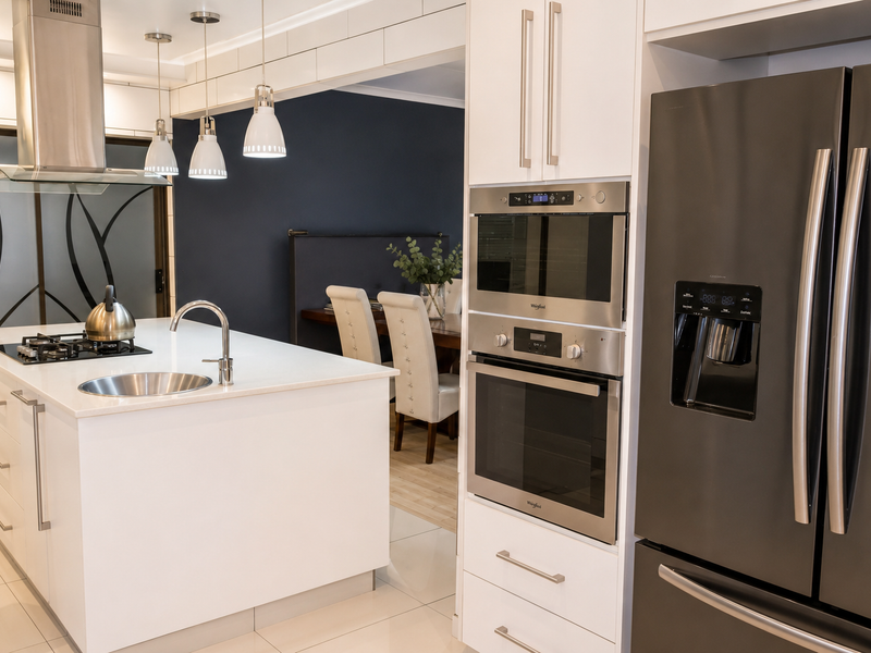 Modern kitchen featuring a central island with gas cooktop, stainless steel appliances, built-in oven and microwave, and sleek white cabinetry with tiled flooring.