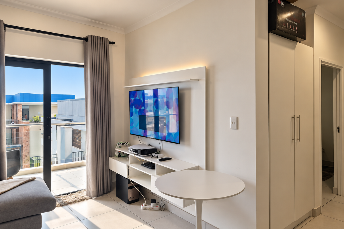 Modern living area featuring a built-in media console, tiled flooring, and a sliding glass door providing access to a private balcony.