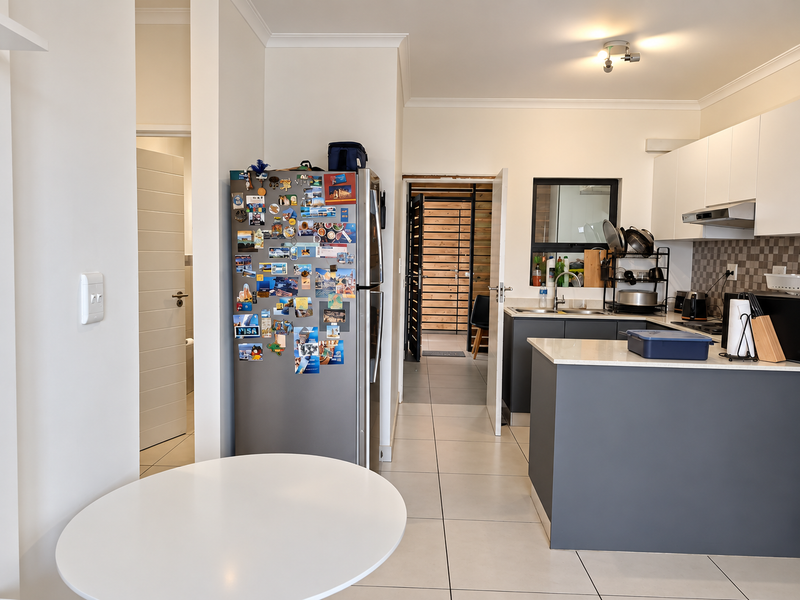 Open plan kitchen area featuring modern cabinetry, a central island, and tiled flooring, providing a functional and bright space for cooking and dining.