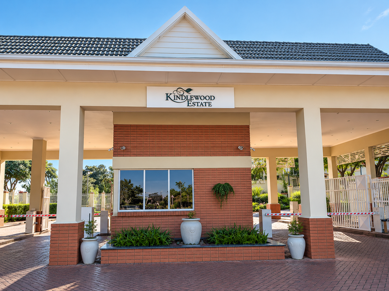 The main entrance gatehouse of Kindlewood Estate, featuring a well-maintained brick facade, paved driveway, and secure access control systems.