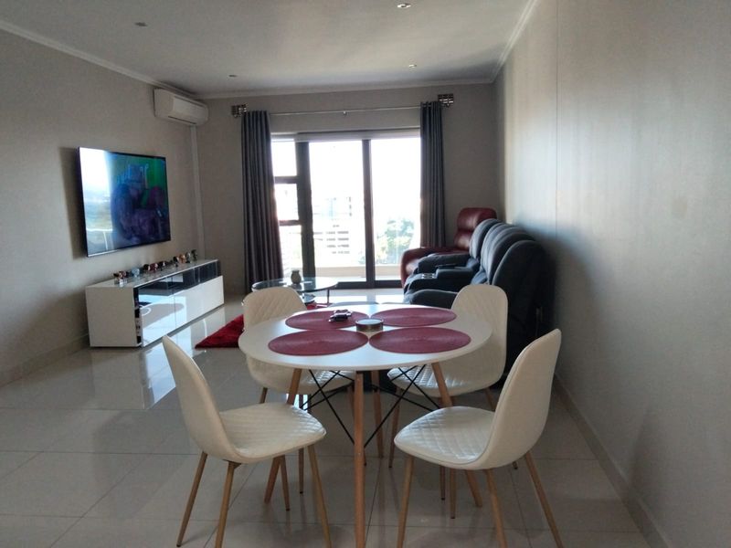 Open-plan living and dining area featuring tiled flooring, recessed lighting, and a sliding glass door leading to a balcony.