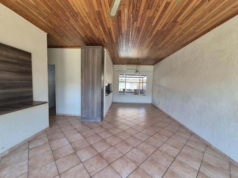 Spacious living area featuring a timber-clad ceiling, tiled flooring, built-in storage, and a wall-mounted air conditioning unit.