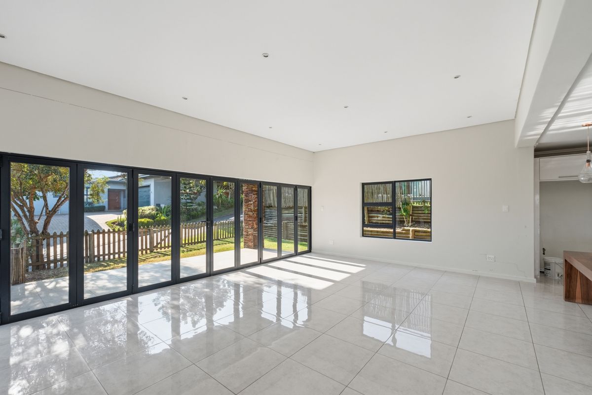 Spacious, light-filled living area featuring large aluminium stacker doors opening to the garden and modern porcelain floor tiles.
