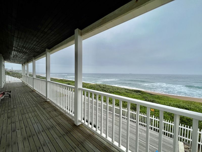Spacious covered timber balcony offering direct ocean views and a coastal outlook, featuring a white balustrade railing.