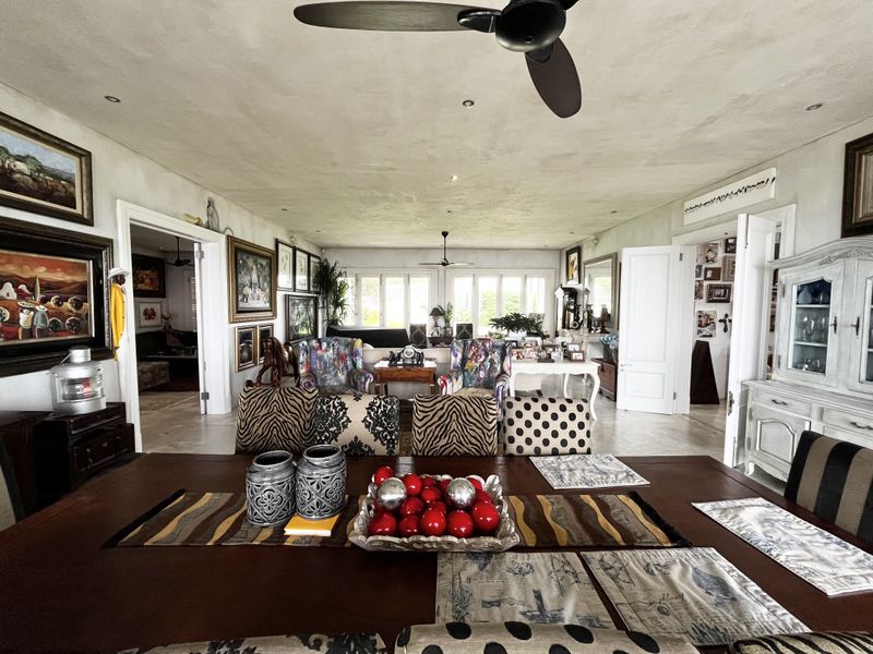 Spacious open-plan living and dining area featuring high ceilings with integrated fans, recessed lighting, and multiple access points to adjacent rooms.