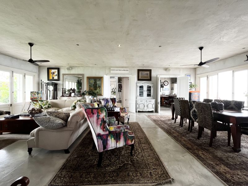 Spacious open-plan living and dining area featuring polished concrete floors, recessed lighting, and dual ceiling fans, with seamless flow between living spaces.