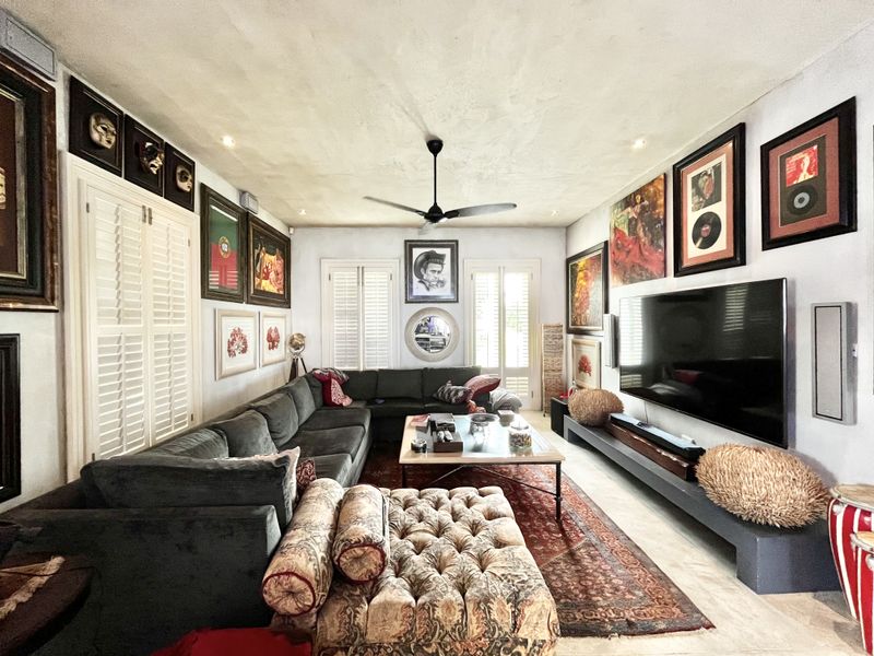 A well-maintained living room featuring plantation shutters, a ceiling fan, recessed lighting, and a custom built-in media console.