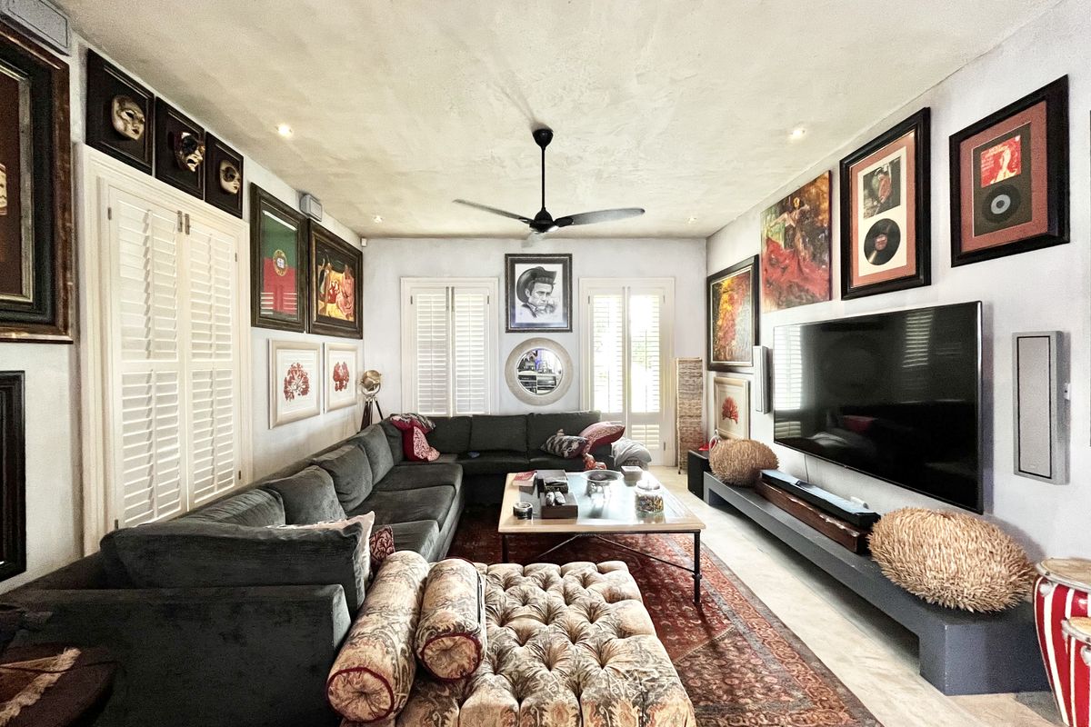 A well-maintained living room featuring plantation shutters, a ceiling fan, recessed lighting, and a custom built-in media console.