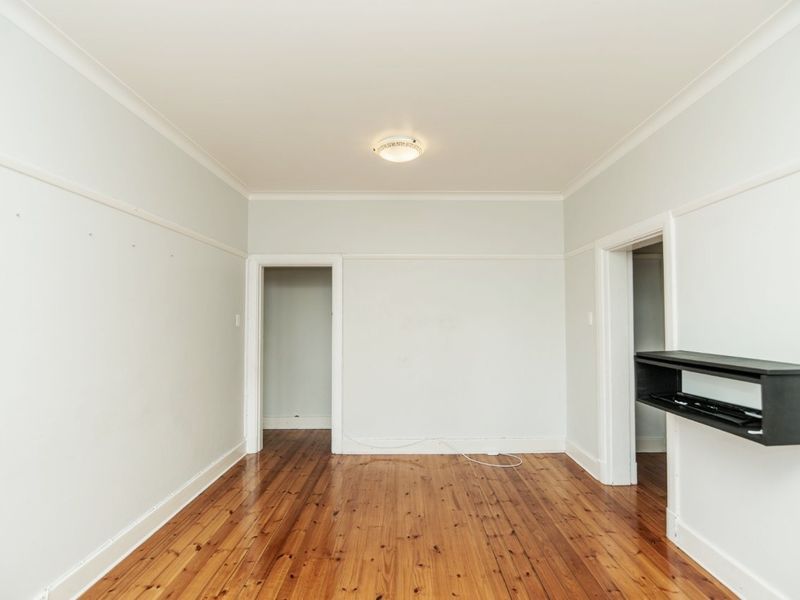 An empty living room featuring polished timber flooring, classic picture rails, and neutral wall finishes, offering a blank canvas for interior design.