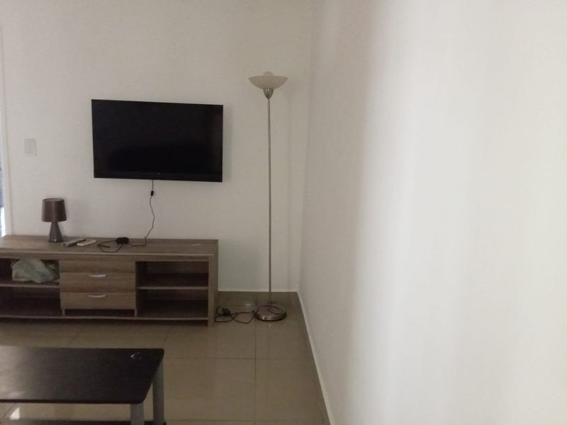 A simple living room area featuring neutral tiled flooring and plain white walls, providing a blank canvas for interior design.