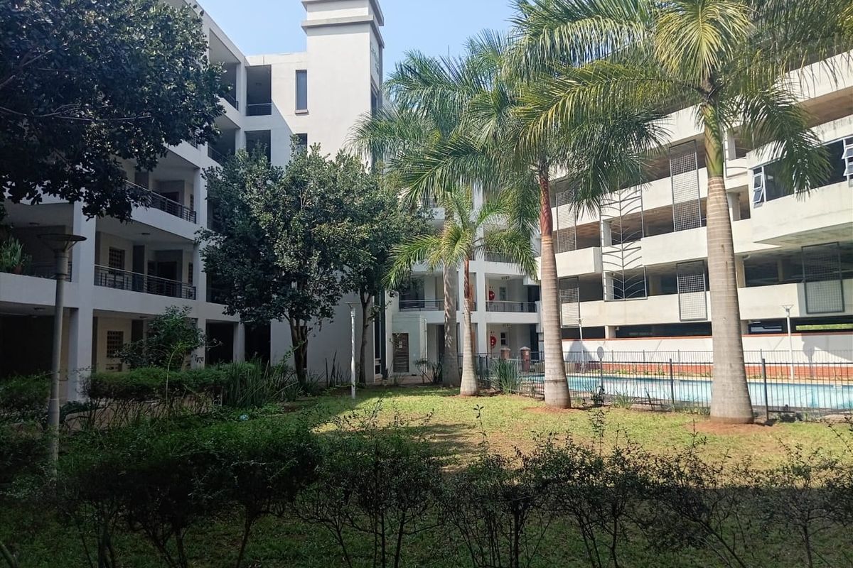 A view of the apartment complex courtyard featuring a landscaped garden, swimming pool, and multi-level balconies.