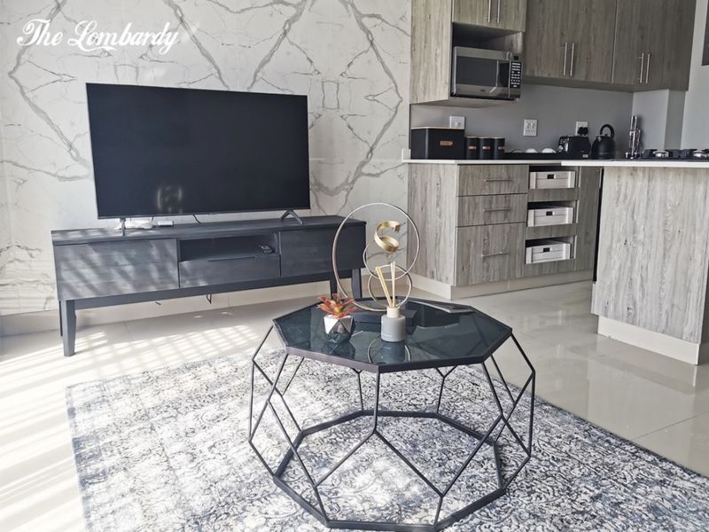 Modern open-plan living area featuring a marble-effect feature wall and a compact, well-appointed kitchen with built-in cabinetry and integrated appliances.