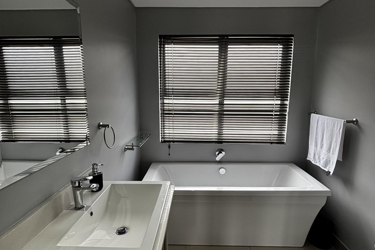 Modern bathroom featuring a sleek freestanding bathtub, contemporary vanity with basin, bidet, and high-quality finishes including recessed lighting and venetian blinds.