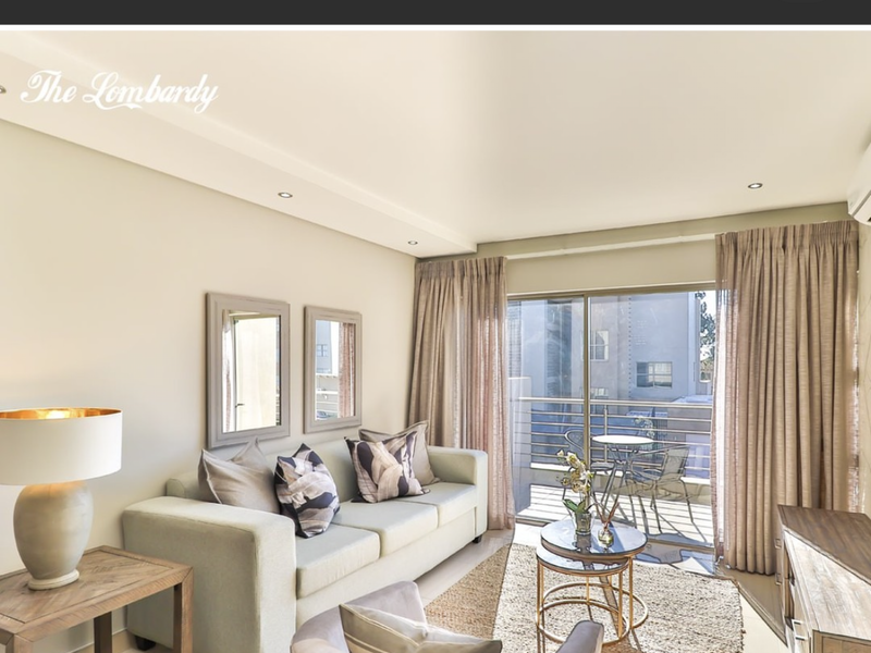 A bright living room featuring recessed downlights and large sliding glass doors leading to an attached balcony.