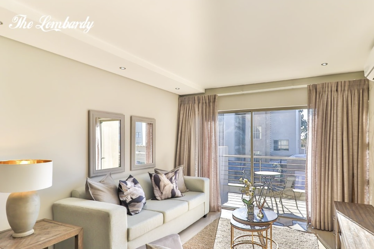 A bright living room featuring recessed downlights and large sliding glass doors leading to an attached balcony.