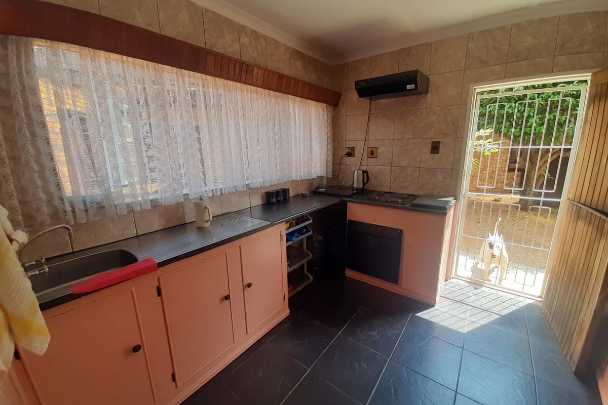 A functional kitchen featuring built-in cabinetry, a built-in oven with hob, extractor fan, and direct access to the rear garden through a security gate.