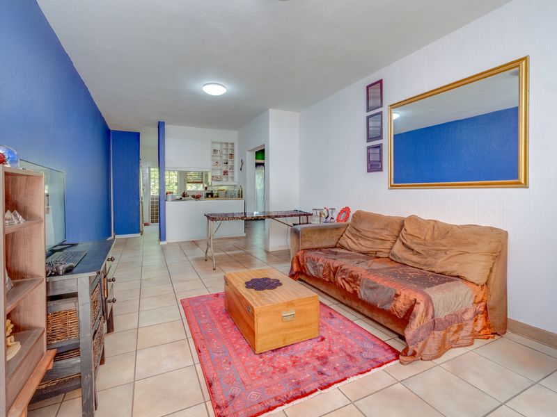 Open plan living area featuring tiled flooring and a pass-through window connecting to the kitchen space.