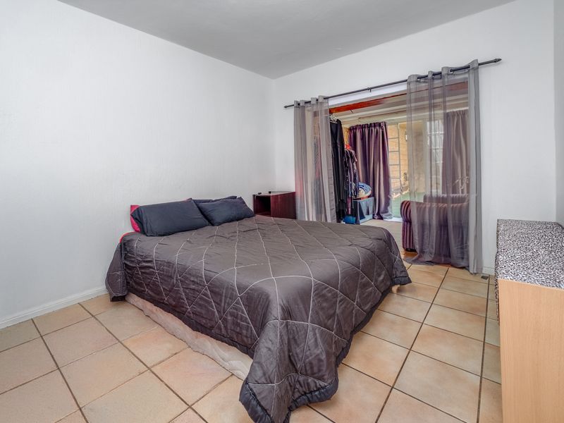 A bedroom featuring tiled flooring and a sliding glass door providing access to an adjacent space.