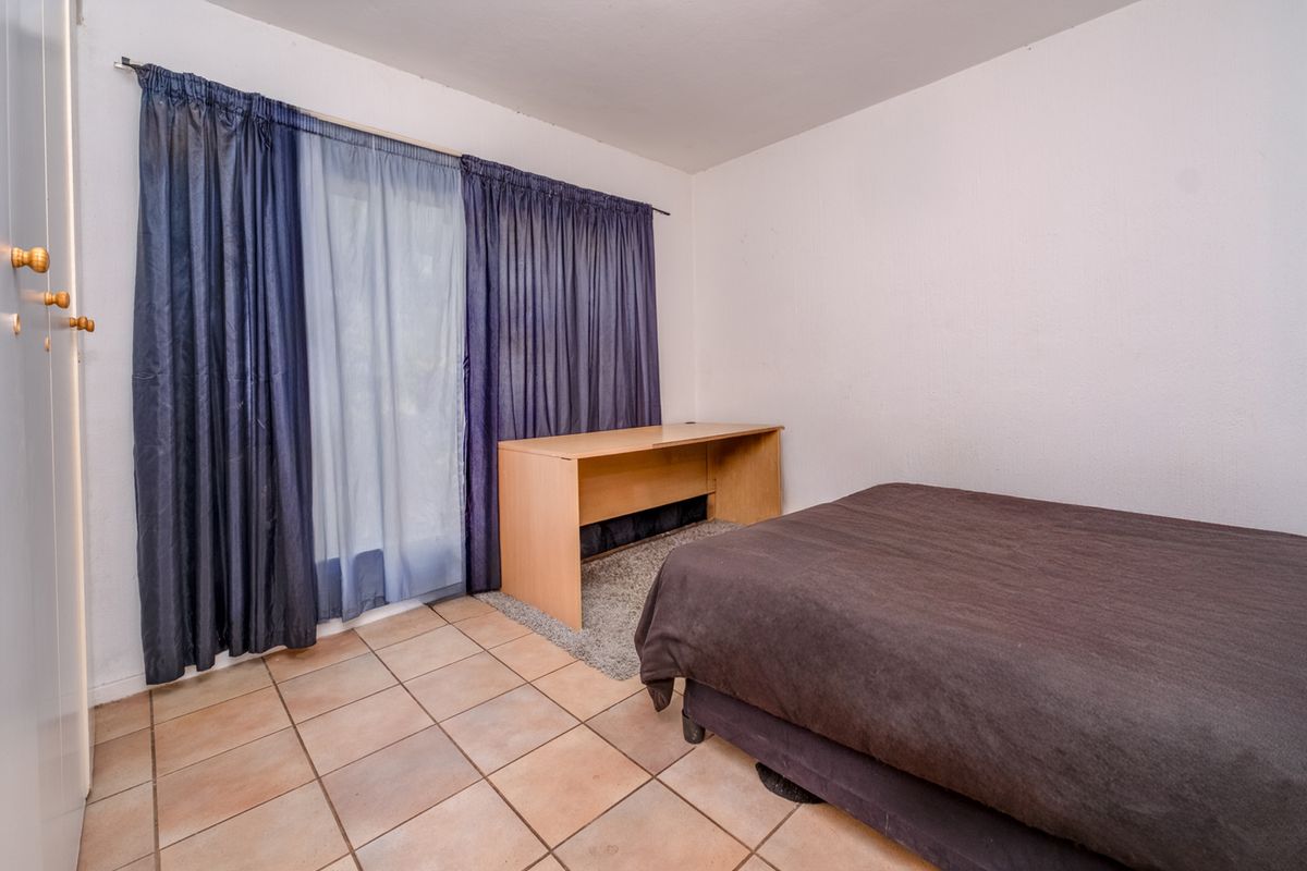 A bedroom featuring tiled flooring and a sliding glass door with curtains, providing access to the exterior.