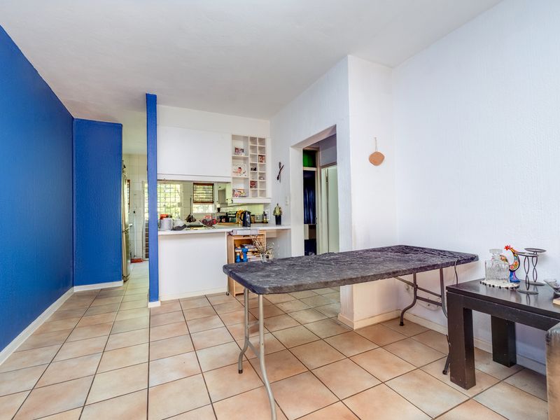 Open-plan living and kitchen area featuring tiled flooring, built-in cabinetry, and a convenient pass-through window connecting the spaces.