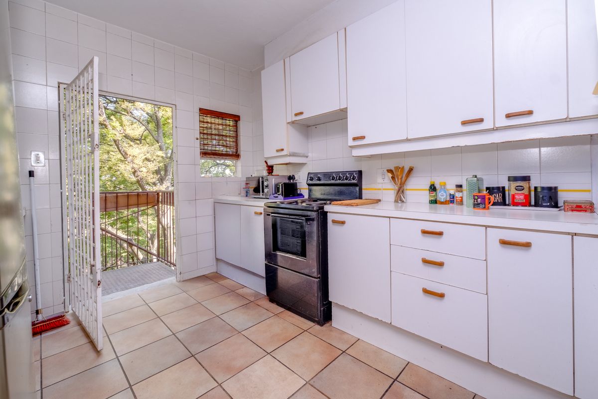 Functional kitchen featuring white cabinetry, tiled backsplash, and direct access to an outdoor balcony area.