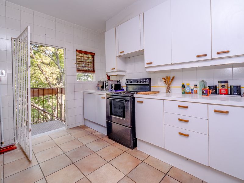 Functional kitchen featuring white cabinetry, tiled backsplash, and direct access to an outdoor balcony area.