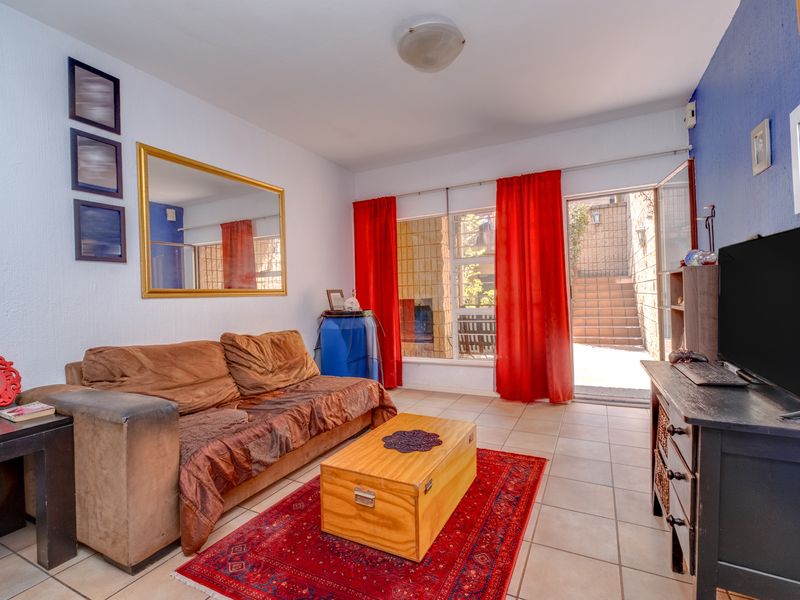 A living room featuring tiled flooring and a sliding glass door providing access to an outdoor area.