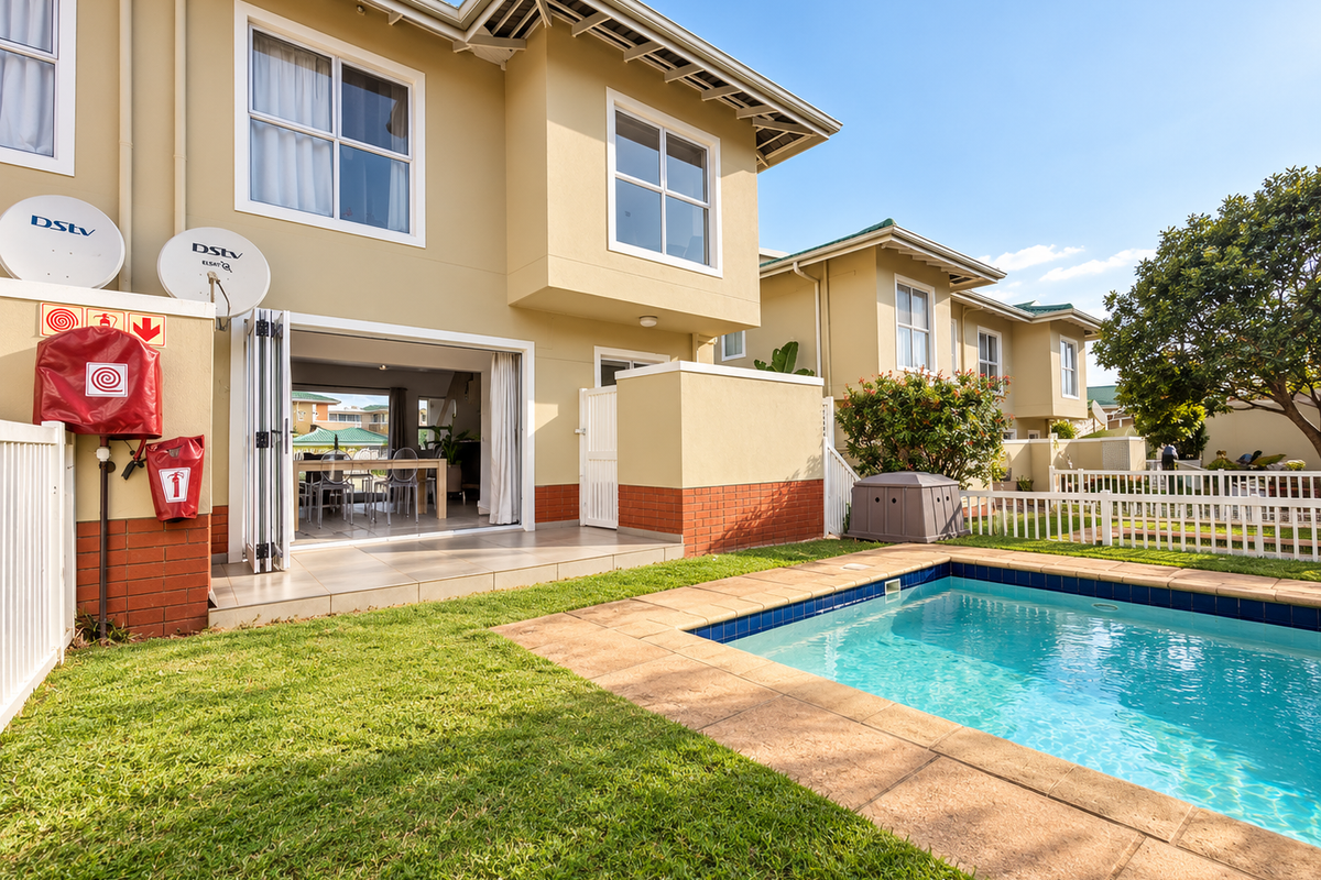 Rear view of a townhouse featuring a private swimming pool, tiled patio area with bi-fold doors, and a well-maintained garden.