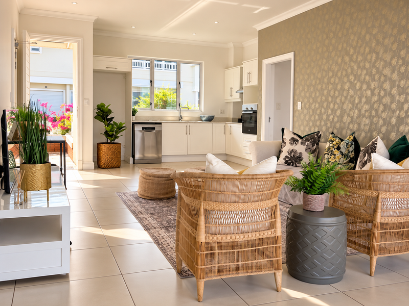 Bright open-plan living area featuring a modern kitchen with built-in appliances, tiled floors, and a stylish feature wall, leading out to a patio.