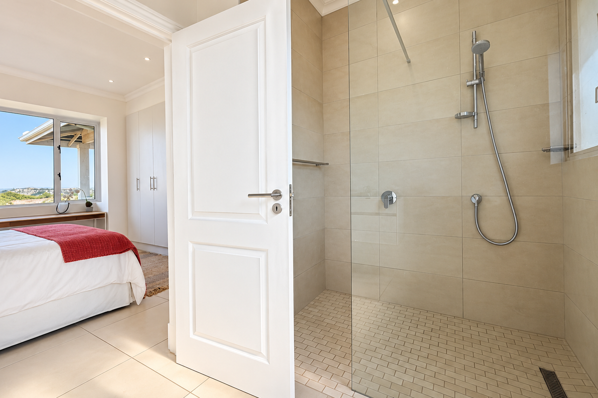Modern bathroom featuring a spacious walk-in shower with glass screen, contemporary tiling, and high-quality fixtures, seamlessly integrated with the adjacent bedroom area.
