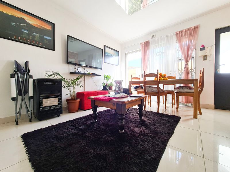 Open-plan living and dining area featuring tiled flooring, large sliding glass doors with security gates, and an integrated intercom system.