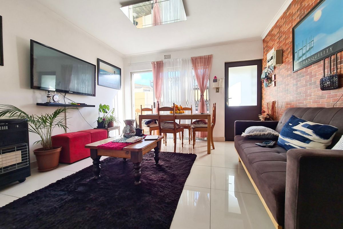 A living room featuring tiled floors, a brick-effect feature wall, and a sliding glass door providing access to the exterior.