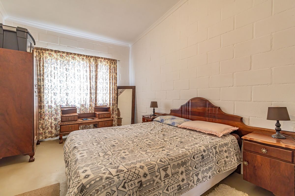 A bedroom featuring exposed white-painted blockwork walls and coved ceiling cornicing, offering a neutral foundation for potential interior updates.
