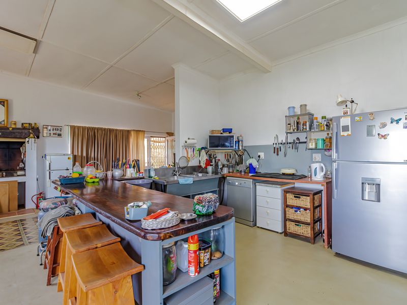 Open-plan kitchen featuring a large wooden island, built-in cabinetry, stainless steel sink, and a traditional fireplace, offering a functional and rustic living space.