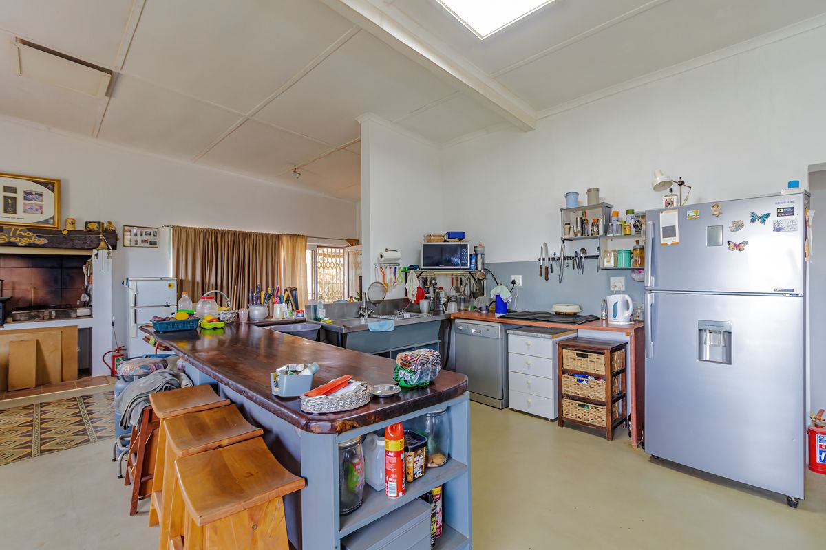 Open-plan kitchen featuring a large wooden island, built-in cabinetry, stainless steel sink, and a traditional fireplace, offering a functional and rustic living space.
