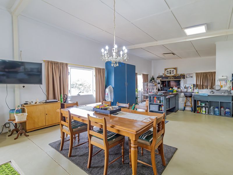 Spacious open-plan living and dining area featuring a central kitchen island, functional cabinetry, and a classic chandelier, offering a versatile layout for family living.