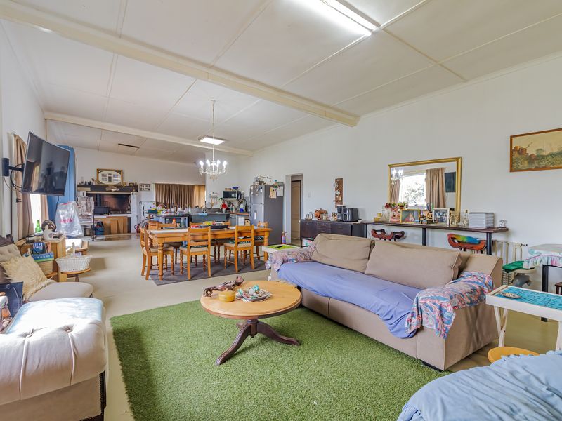 Spacious open-plan living and dining area featuring tiled flooring, exposed beam ceilings, and integrated kitchen space, offering a versatile layout for family living.