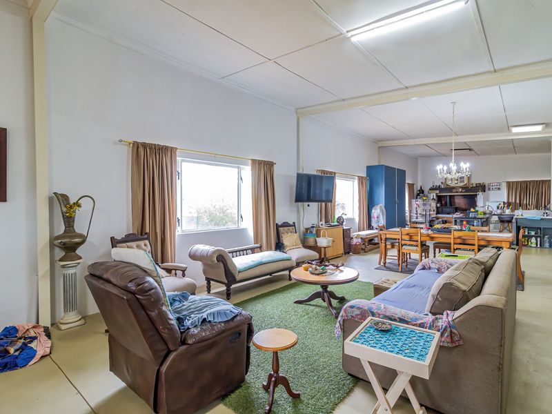 Spacious open-plan living and dining area featuring tiled floors, exposed ceiling beams, and an integrated kitchen space.