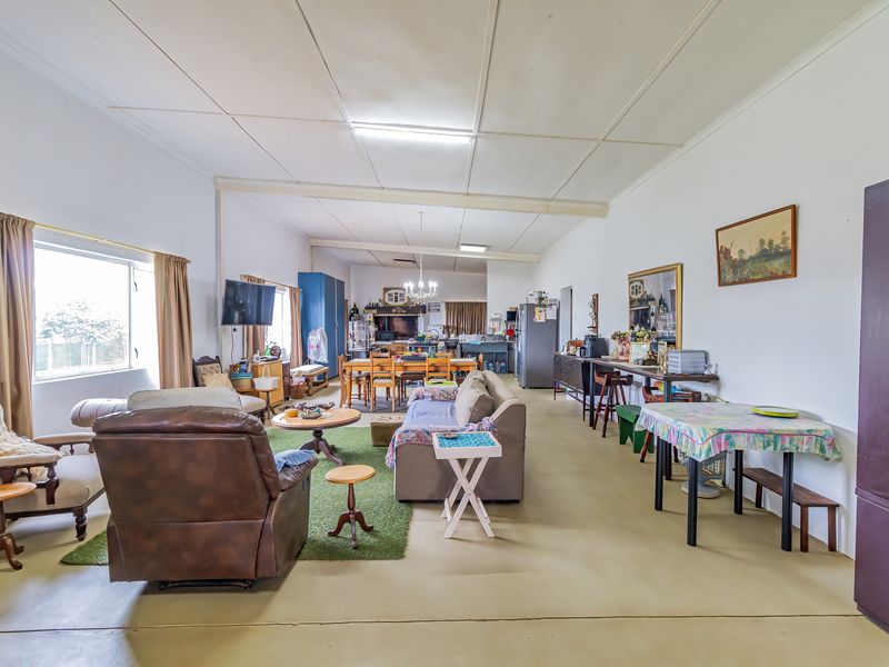 Spacious open-plan living, dining, and kitchen area featuring tiled flooring and functional layout, offering significant potential for modern renovation and aesthetic updates.