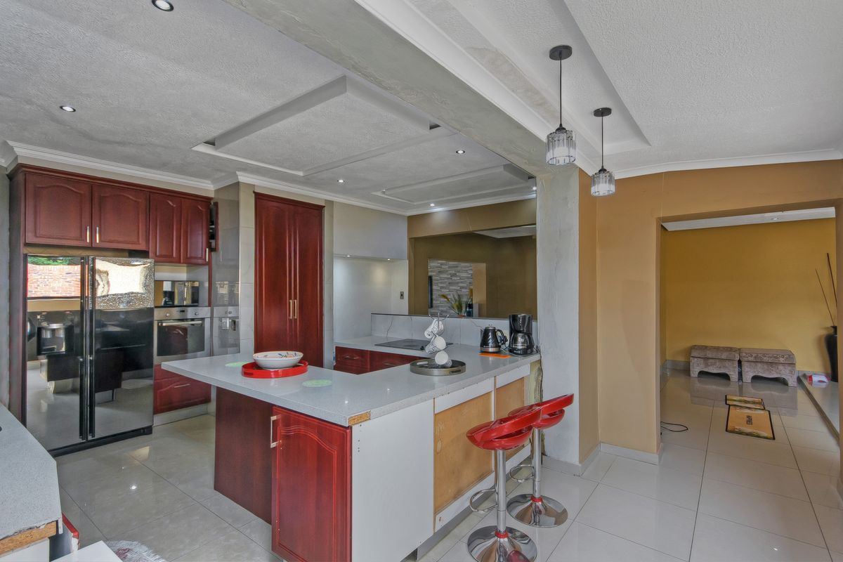 Kitchen featuring dark wood cabinetry, stone countertops, a breakfast bar, and tiled flooring, with some areas requiring finishing touches.