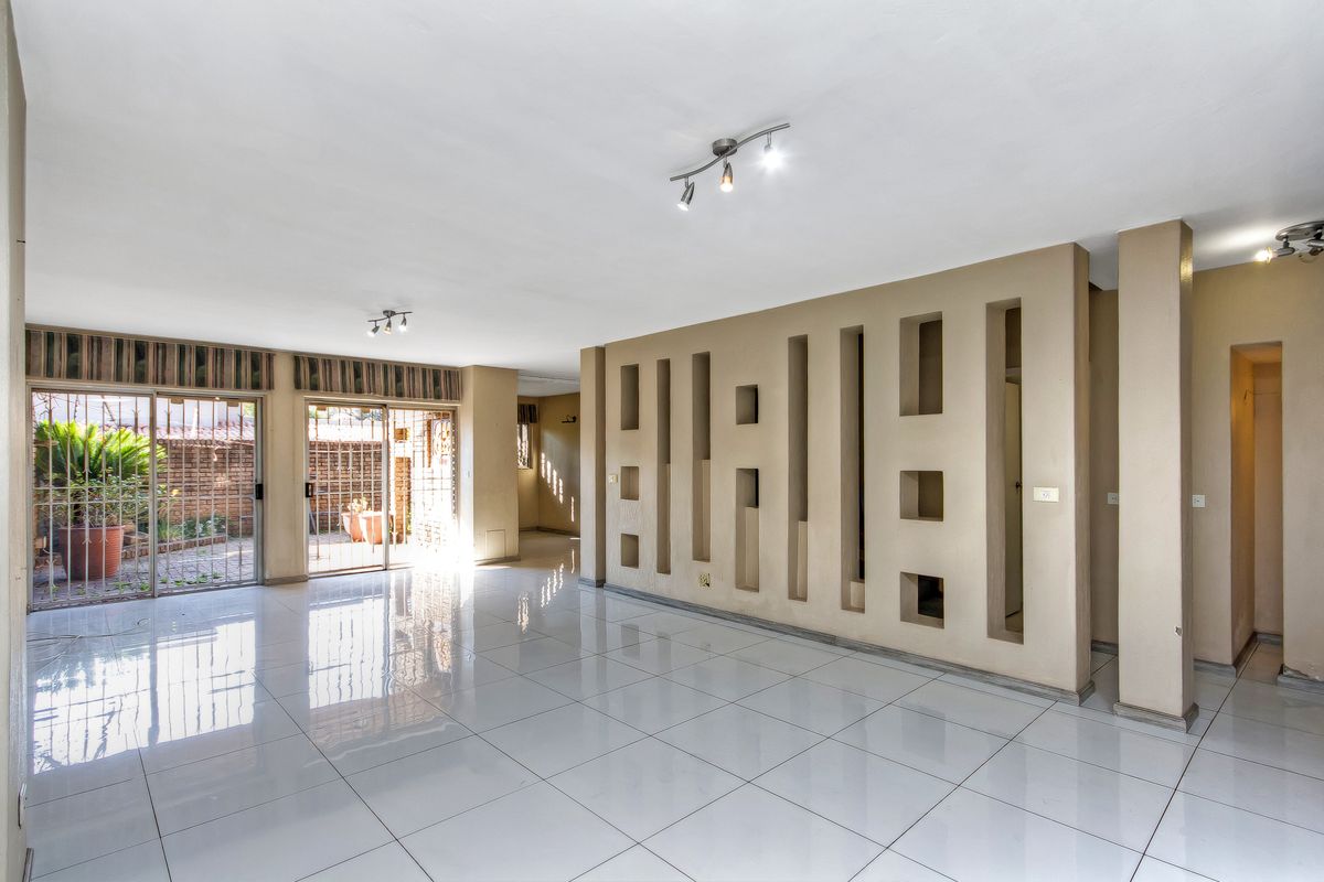Spacious, empty living area featuring polished tiled floors, a unique decorative partition wall, and sliding glass doors providing access to the outdoor patio.