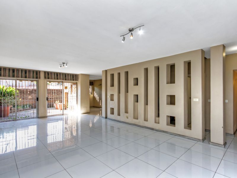 Spacious, empty living area featuring polished tiled floors, a unique decorative partition wall, and sliding glass doors providing access to the outdoor patio.