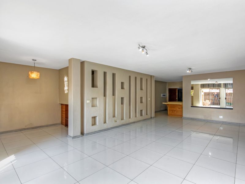Spacious open-plan living area featuring large format floor tiles, a unique decorative partition wall, and a built-in breakfast bar counter.