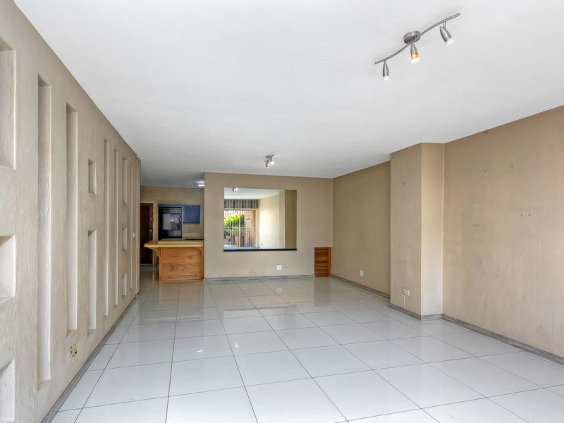 Spacious open-plan living area featuring tiled flooring, unique recessed wall niches, and a convenient breakfast bar connecting to the kitchen space.