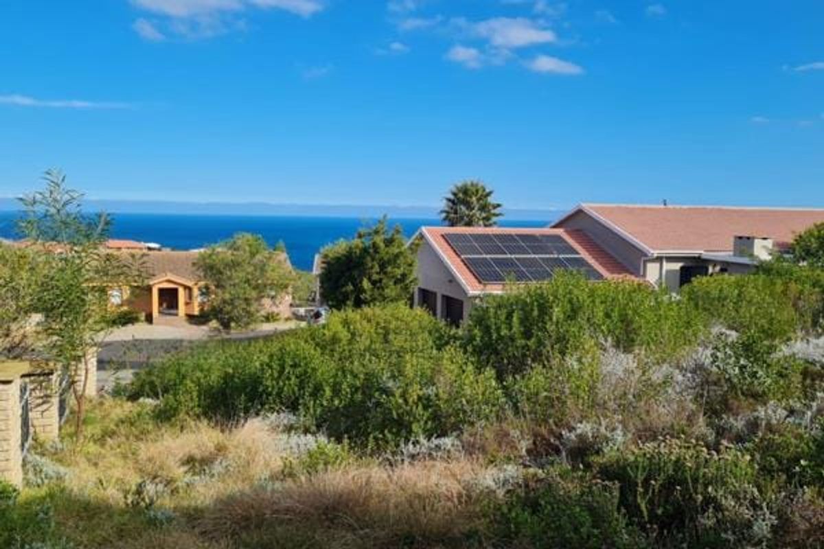 A scenic view overlooking a residential area with coastal ocean vistas and visible solar panel installations on neighboring rooftops.