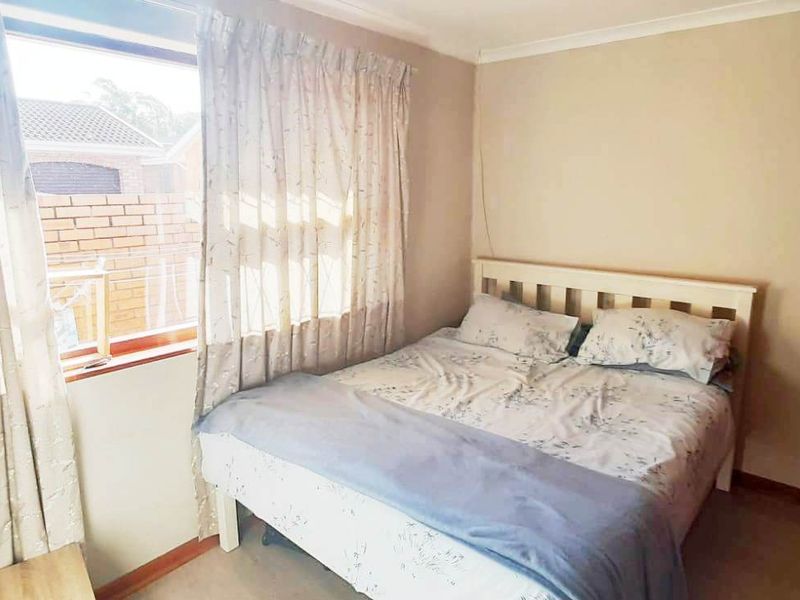 A standard bedroom featuring carpeted flooring, a built-in wardrobe, and a window with natural light.