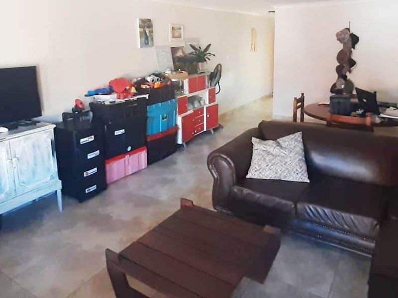 An open-plan living and dining area featuring neutral walls and tiled flooring, providing a versatile space for relaxation and meals.