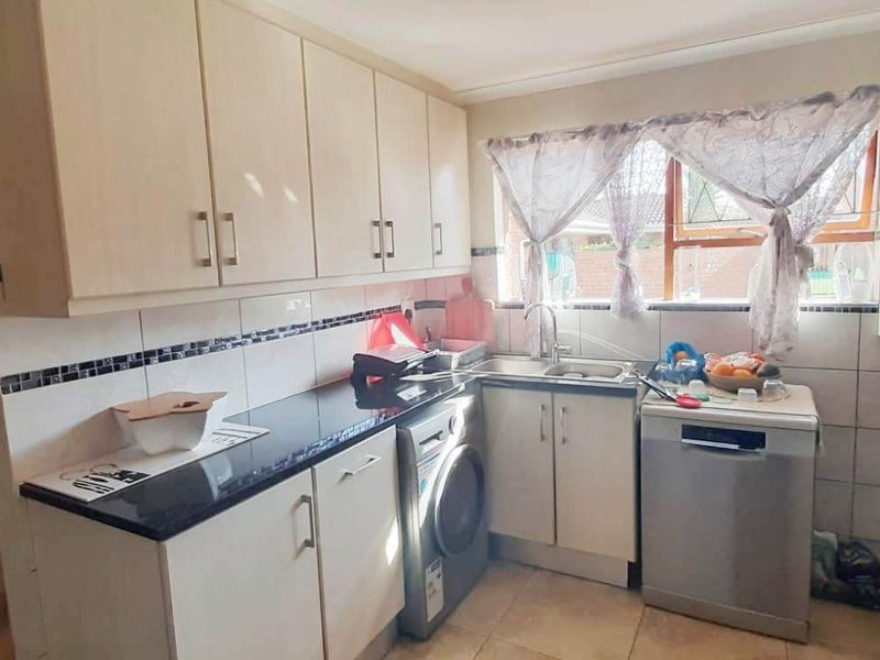 Functional kitchen featuring ample built-in cabinetry, granite countertops, tiled backsplash, and integrated space for laundry and dishwashing appliances.