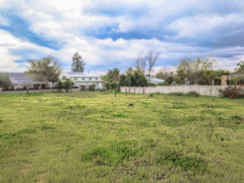 A vacant residential plot of land featuring open grass area and perimeter fencing, suitable for future development.